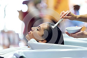 The hairdresser applying hair treatment for customer in a beauty salon.