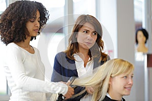hairdresser apprentice doing hairdo to client