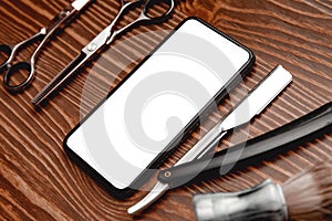 Hairdresser barber shop tools with mobile phone screen on old wooden background, copy space