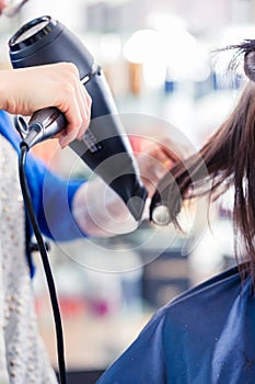 Hairdresser blow dry woman hair in shop