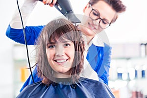 Hairdresser blow dry woman hair in shop