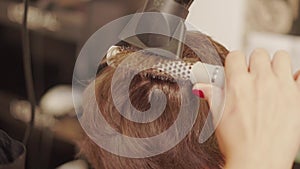 Hairdresser blow-drying hair, paddle brush on woman head