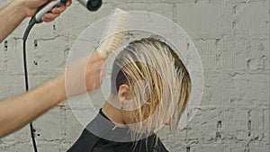 Hairdresser blowing with hairdryer woman's hair at the beauty salon