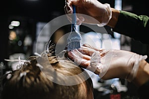 Hairdresser with a brush to apply hair dye. Coloring in the barber shop