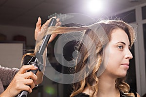 Hairdresser carefully making hair curling to a client