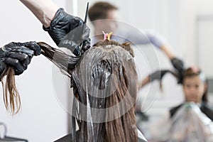 A hairdresser coloring hair of a female client