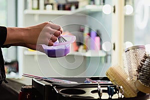 Hairdresser colorist kneads paint for hair dyeing.