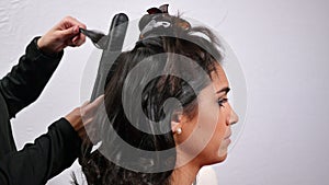 Hairdresser combing and curling a young girl`s hair