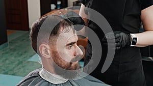 Hairdresser combing wet hair bearded man before haircut. Barber combing male hair for hairdressing in male salon