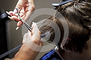 hairdresser creates a fashionable haircut for a tenager boy