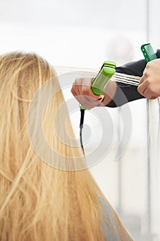 Hairdresser curling hair with straightener