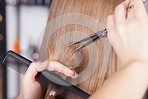 Hairdresser cut blond hair of a woman
