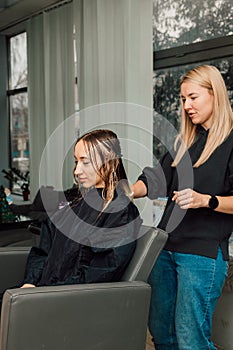 A hairdresser cuts a blonde& x27;s hair in a beauty salon. Women& x27;s haircut