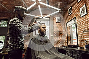 The hairdresser cuts and combs client& x27;s hair with a comb. Young men in a barbershop