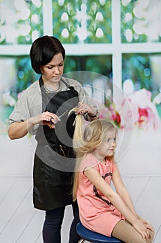 Hairdresser cuts girl long hair