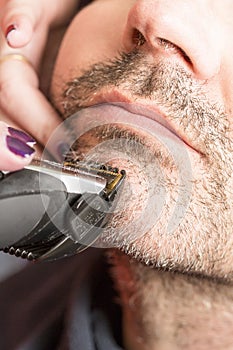 Hairdresser, cutting beard in her work place