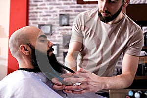 Hairdresser cutting a client`s beard with scissors