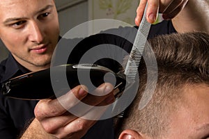 Hairdresser cutting clients hair with an electric hair clipper