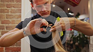 Hairdresser cutting the edges of female client hair with a thin comb in his hand