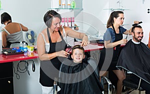 Hairdresser cutting hair of boy