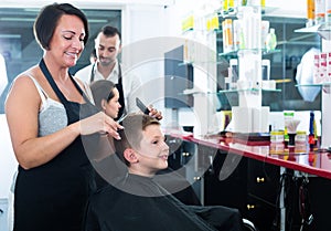 Hairdresser cutting hair of boy