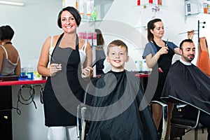 Hairdresser cutting hair of boy