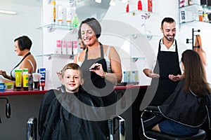 Hairdresser cutting hair of boy