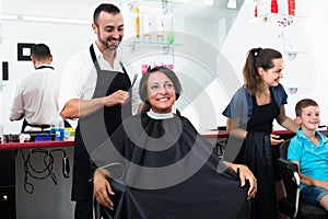 Hairdresser cutting hair of female client