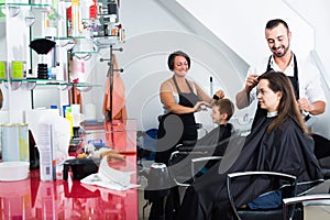 Hairdresser cutting hair of female client