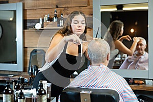 Hairdresser cutting hair of male client. Hairstylist serving client at barber shop