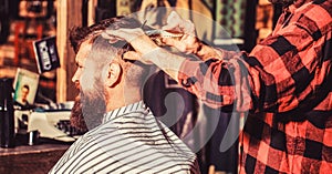 Hairdresser cutting hair of male client. Man visiting hairstylist in barbershop. Barber scissors. Bearded man in barber