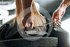 Hairdresser cutting hair to beautiful young woman