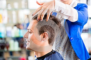 Hairdresser cutting man hair in barbershop