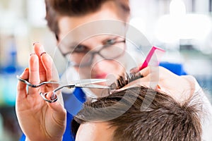 Hairdresser cutting man hair in barbershop