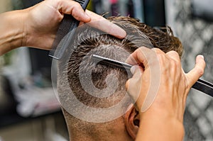 Hairdresser cutting man's hair with toothed razor