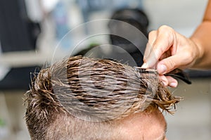 Hairdresser cutting man's hair with toothed razor