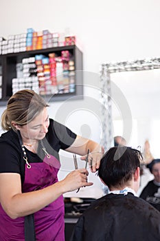 Hairdresser cutting and modelling brown hair by scissors and comb
