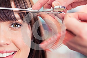 Hairdresser cutting woman bangs hair