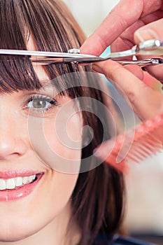 Hairdresser cutting woman bangs hair