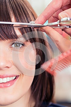 Hairdresser cutting woman bangs hair photo