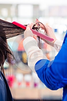 Hairdresser cutting woman hair in shop
