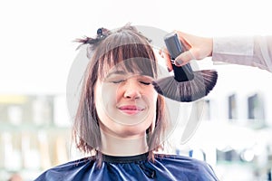 Hairdresser cutting woman hair in shop