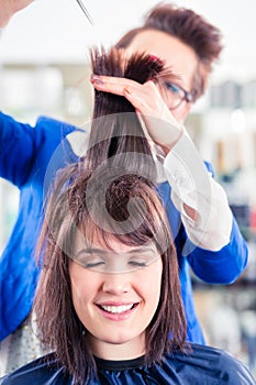 Hairdresser cutting woman hair in shop