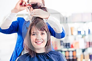 Hairdresser cutting woman hair in shop