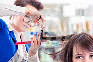 Hairdresser cutting woman hair in shop