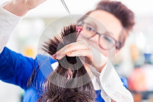 Hairdresser cutting woman hair in shop