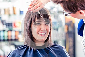 Hairdresser cutting woman hair in shop photo
