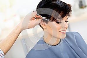 Hairdresser Cutting Woman's Hair in Beauty Salon. Haircut photo