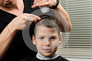 Hairdresser does a haircut for the boy and applies a remedy for easy combing