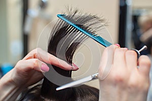 The hairdresser does a haircut of hair to a young girl, a brunette